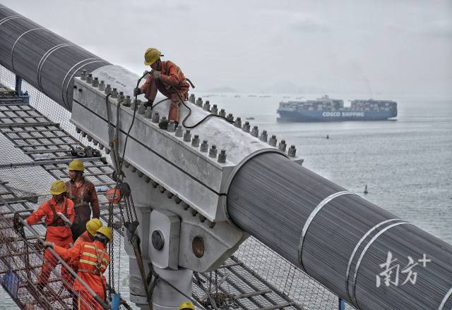 正在施工中的建設(shè)者身后，海上船舶往來不斷。  
