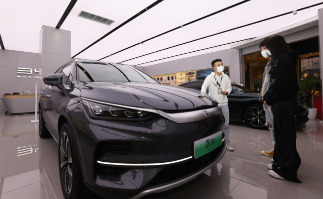 比亞迪店內(nèi)，一名銷售人員（左）正在向兩位顧客介紹車輛信息。深圳特區(qū)報記者 楊浩翰 攝