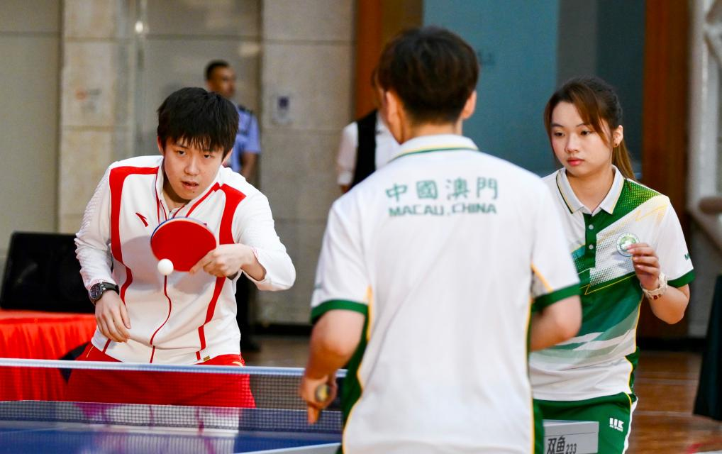 9月1日，乒乓球運動員王楚欽（左）與澳門運動員切磋球技。當日，內地奧運健兒代表團在澳門奧林匹克體育中心室內體育館與澳門青少年運動員進行互動交流。新華社記者 郭雨祺 攝