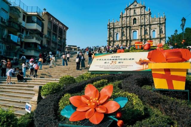 12月5日，澳門大三巴牌坊，“熱烈慶祝中華人民共和國澳門特別行政區成立25周年”的標志吸引游客留影。圖/視覺中國