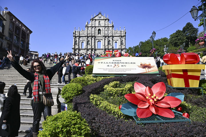 游客在澳門大三巴牌坊慶祝布景旁留影（2024年12月18日攝）。新華社記者 程一恒 攝