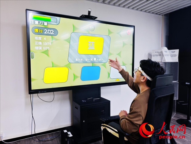 廣州琶洲實驗室工作人員演示腦機接口設備如何操作專注力訓練游戲。人民網 樸馨語攝