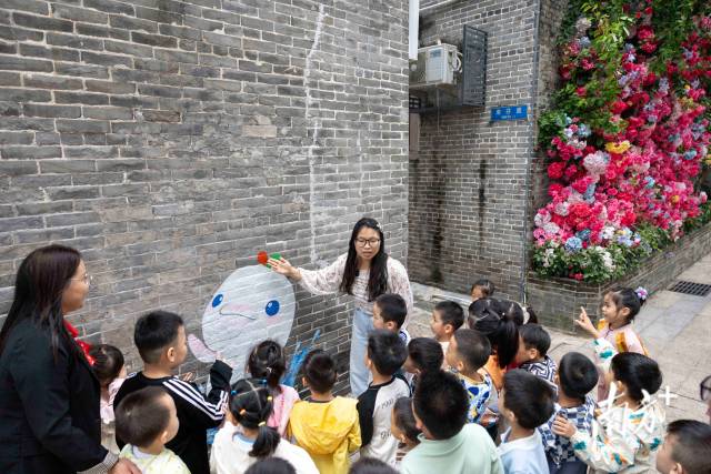 老師在給小朋友介紹十五運吉祥物“喜洋洋”頭上的三色水花背后的含義。