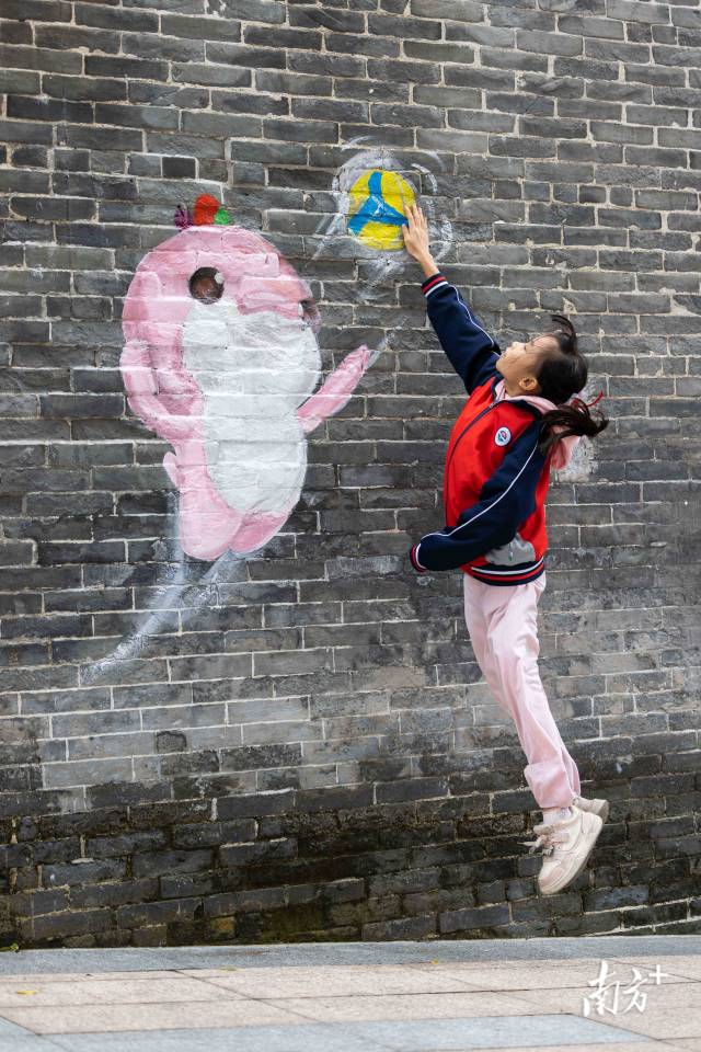 小朋友躍起與“樂融融”墻繪打排球互動。